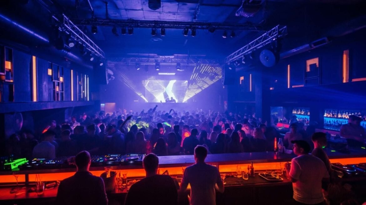 Energetic crowd dancing in a modern Moscow nightclub with international DJs, strobe lights, and bartenders serving cocktails at a neon-lit bar.