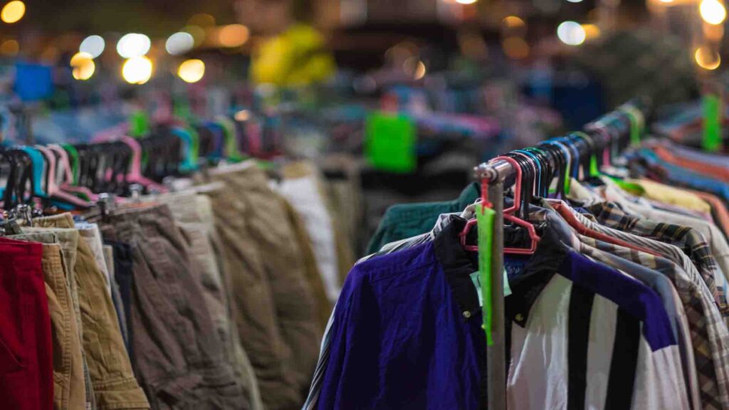 Second-hand clothes hanging in a street market with vintage garments, casual racks, and local shopping atmosphere