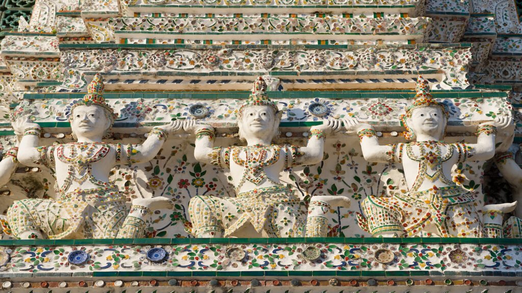 Sacred sculptures decorating the main prang of Wat Arun Temple, showcasing iconic Buddhist architecture in Bangkok, Thailand