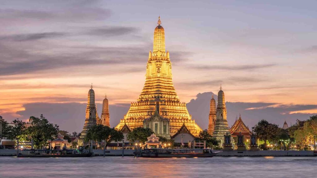 Wat Arun Temple at sunset reflecting golden light over the Chao Phraya River in Bangkok, Thailand