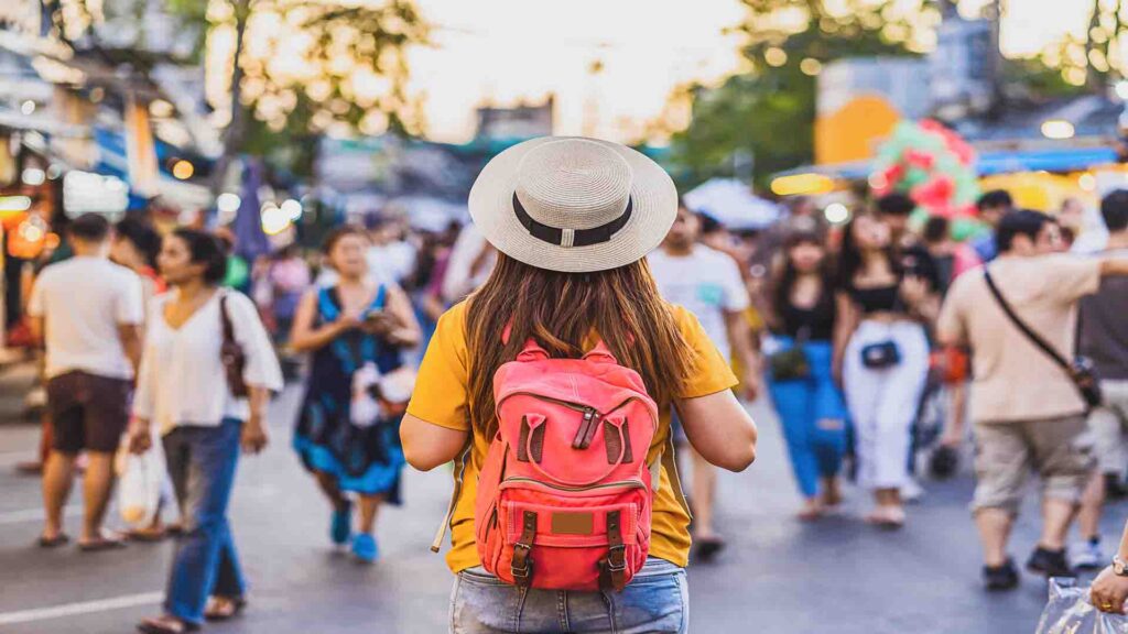 Women walking and browsing stalls at Chatuchak Weekend Market in Bangkok, surrounded by colorful shops and lively market atmosphere