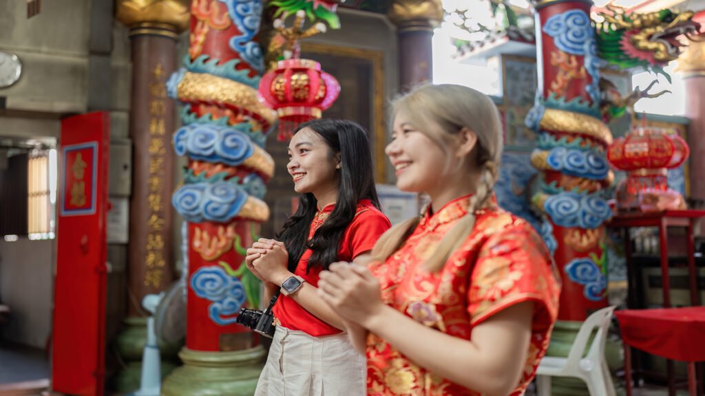 Joyful women in traditional attire celebrating Chinese New Year at a cultural temple