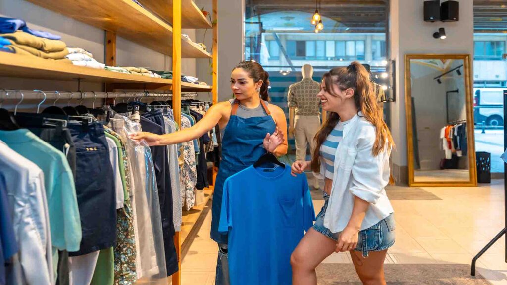 Shop assistant showing clothes to a customer inside a boutique, highlighting personal service and modern retail experience
