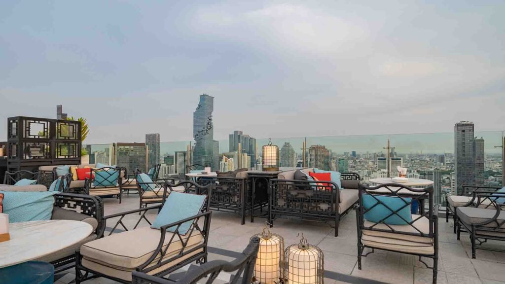 Sky bar rooftop restaurant with dinner tables overlooking a city skyline