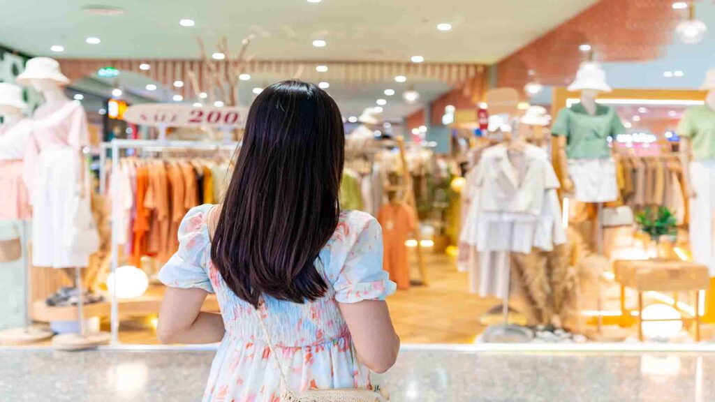 Young Asian woman choosing clothes inside a clothing store at a shopping mall