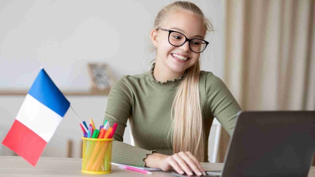 Cheerful woman using a laptop while holding the flag of France