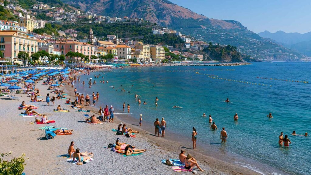 Travelers enjoying Maiori's public beach on the Amalfi Coast, with clear water, coastal scenery, and free beach access