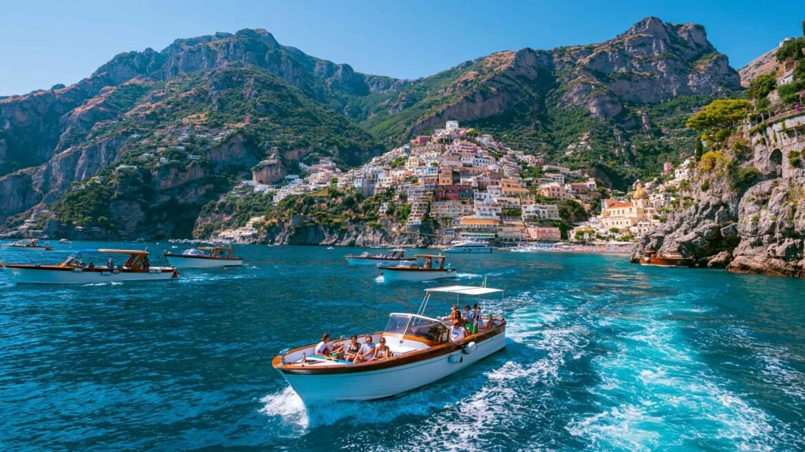 Best Boat Tours in Positano featuring traditional tour boats cruising past the colorful cliffside village along the Amalfi Coast.