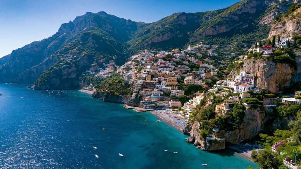 Best Boat Tours in Positano view showing Positano’s coastline, beaches, cliffs, and calm blue waters on a sunny summer day.