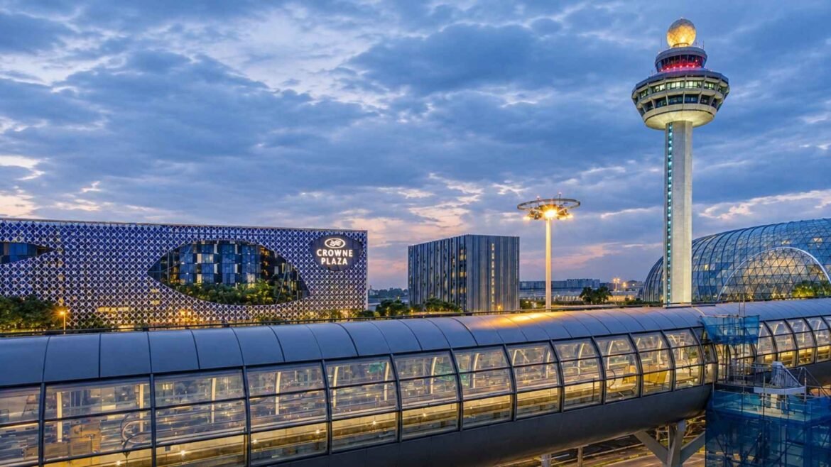 Hotels near Singapore Changi Airport – Crowne Plaza’s illuminated façade beside the airport control tower at dusk.